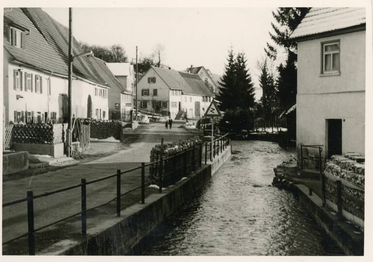 Historische Schwarzweißfotografie einer Straße in Gomadingen. Darauf zu sehen ist die Lauter.