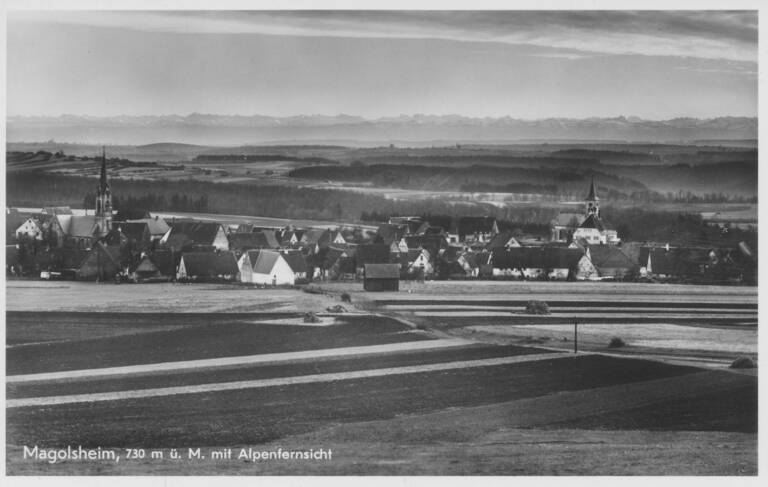 Historische Schwarzweißfotografie von Münsingen-Magolsheim in Form einer Ansichtskarte. Unten links die Aufschrift "Magolsheim, 730m ü.M. mit Alpenfernsicht".